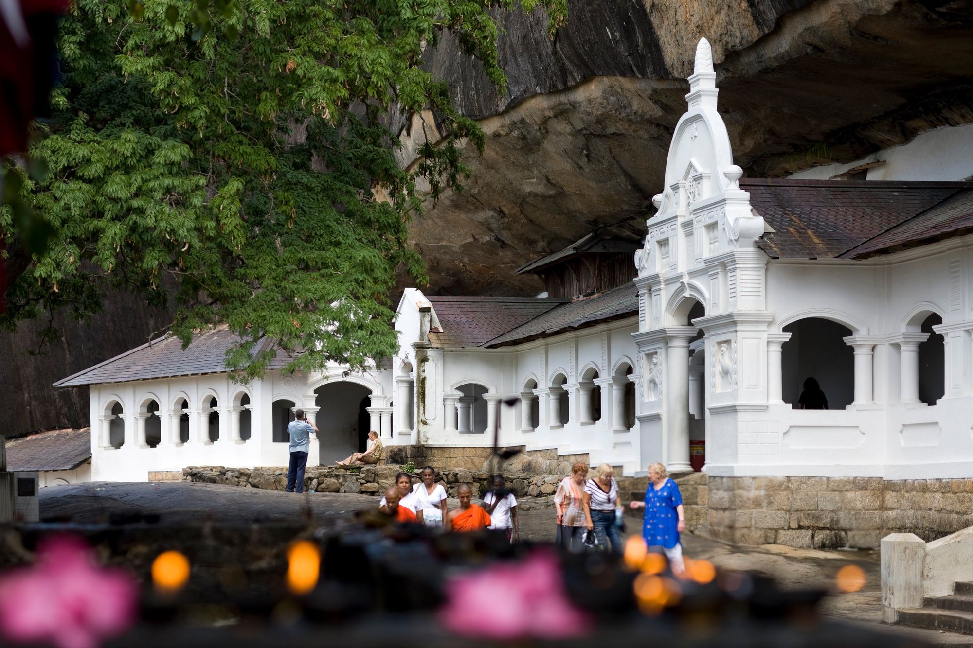 The white entrance buildings of the Dambulla cave temple under the overhanging rock