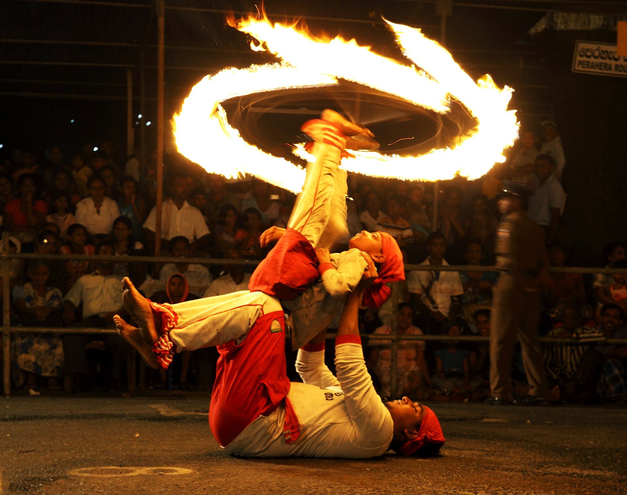 A Perahera performer spins a ring of fire at night in Kandy