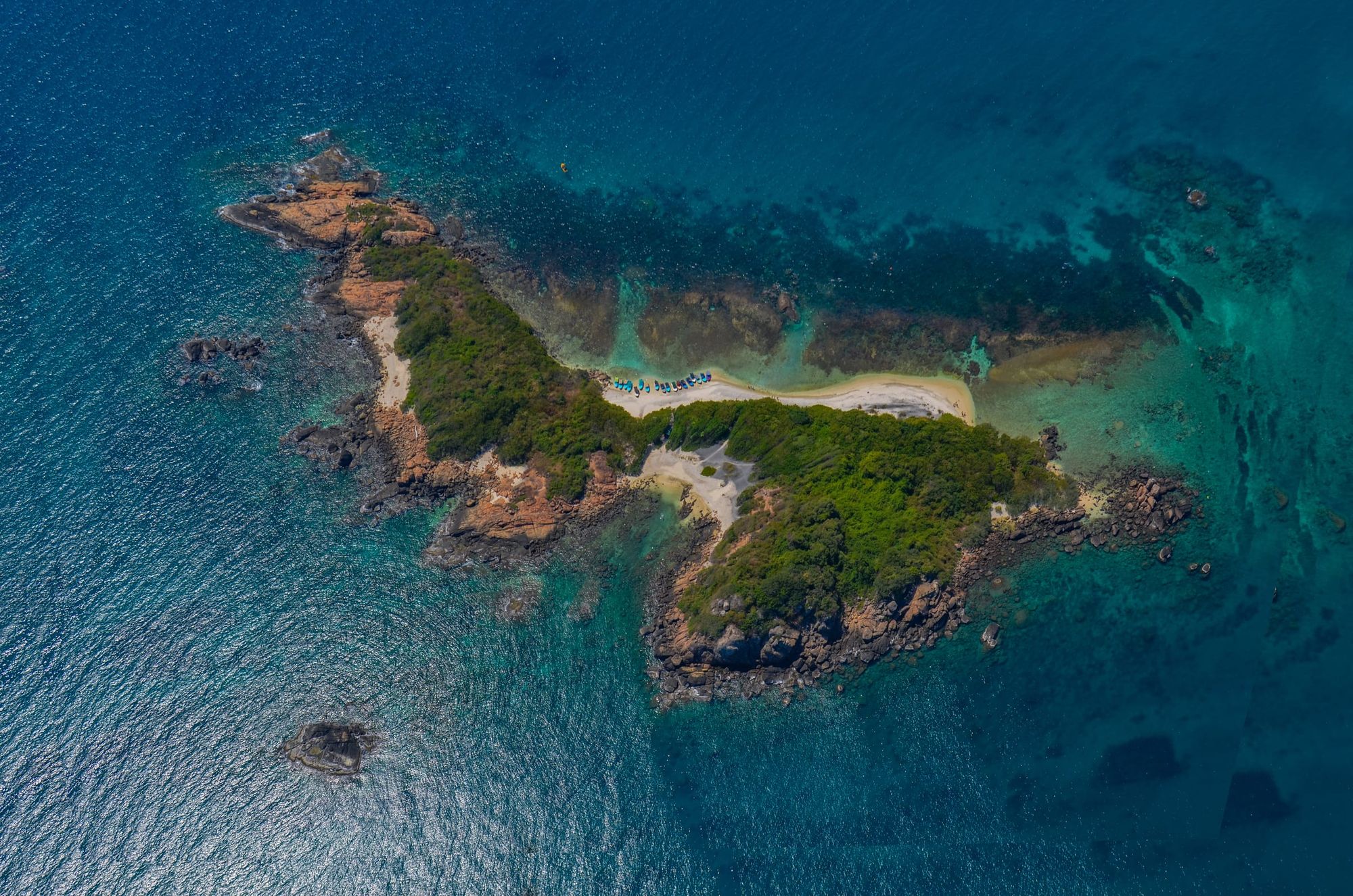 Pigeon Island from the air: a small green island ringed by rocks in deep blue sea