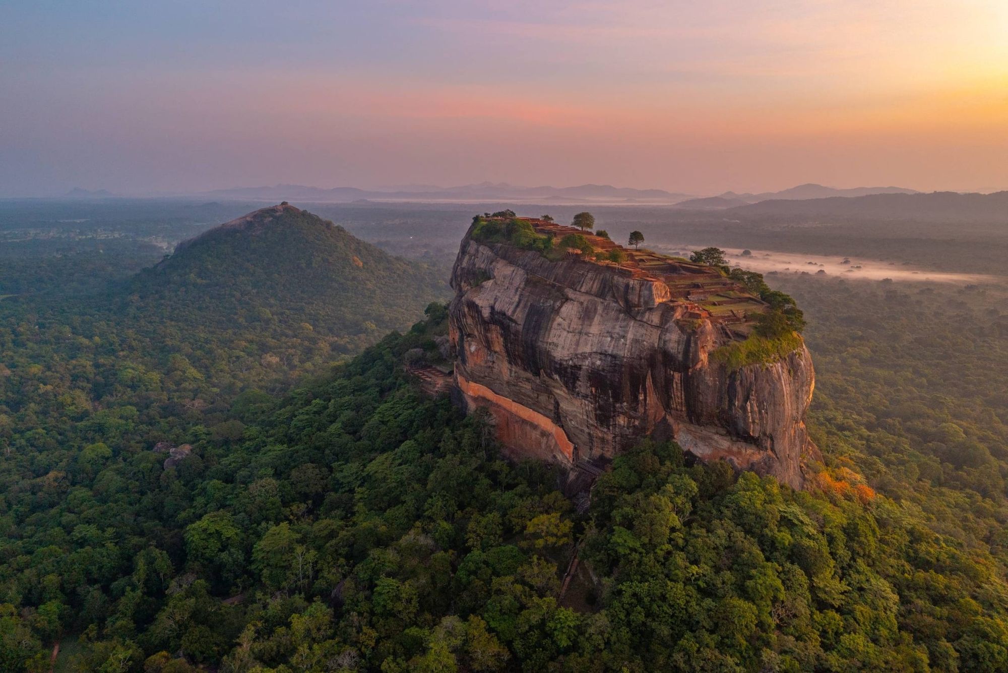 Sigiriya rock fortress rising from the forest at sunrise, seen from the air