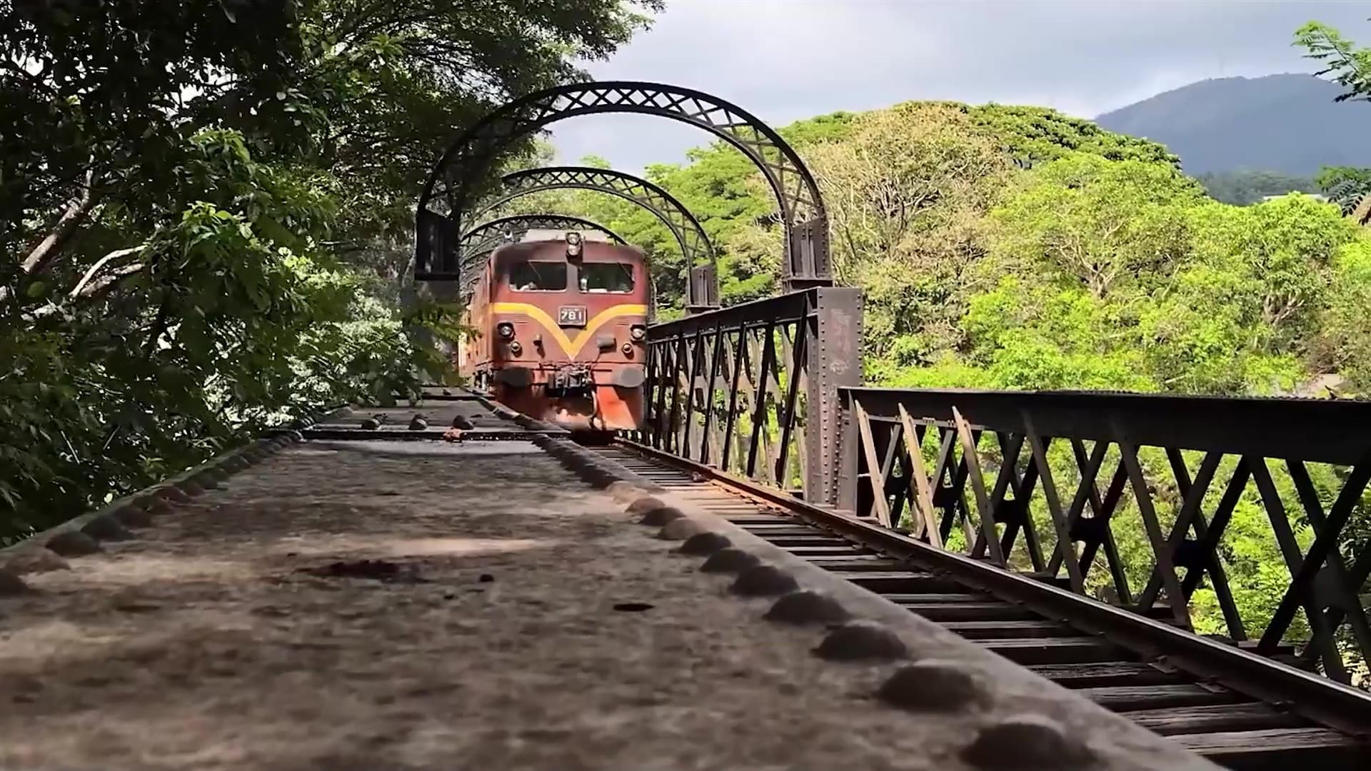 A train coming through an iron bridge in the hills
