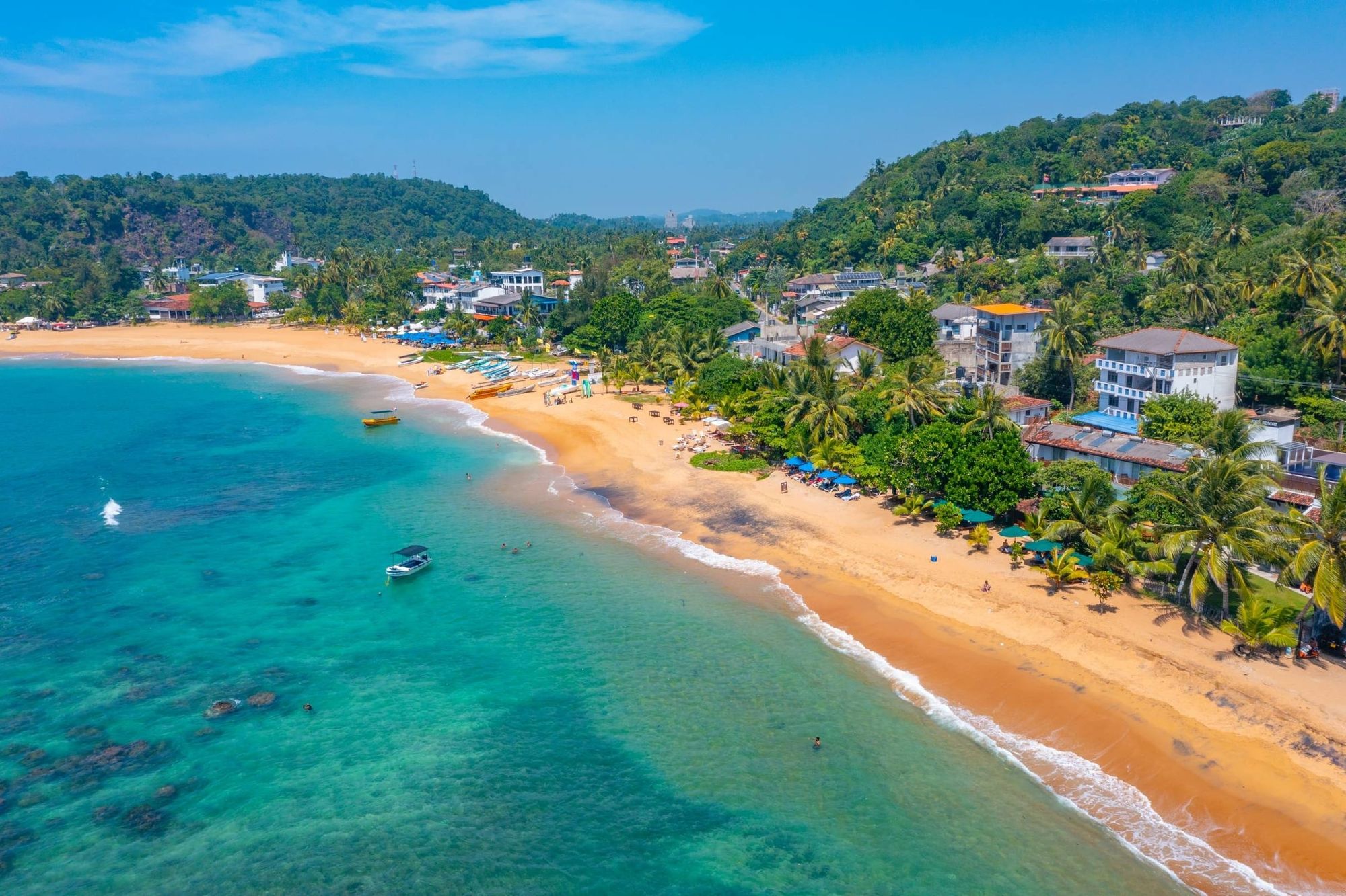 Unawatuna bay from the air: turquoise water, a curve of sand and hotels among the palms